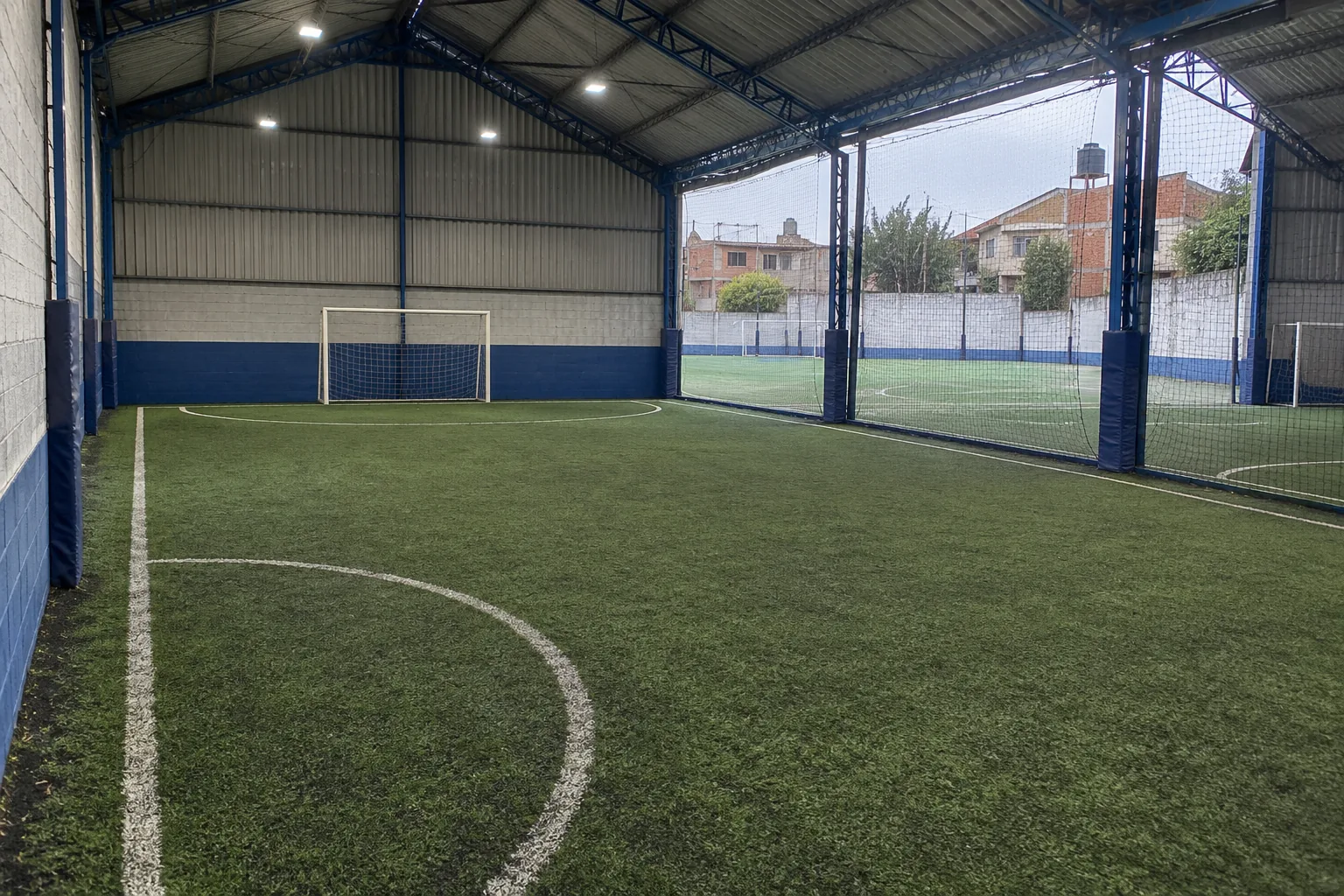 Cancha de fútbol 5 techada de El Potrero, con vigas azules y césped sintético